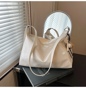 Detail of white glossy leather tote bag with sports charms and macro texture view