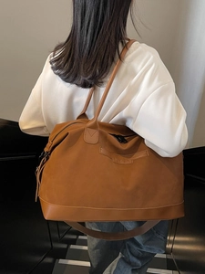 Grand sac cabas marron porté par un modèle avec fines bandoulières et fermeture éclair