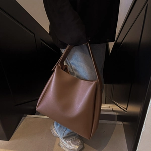 Close-up of a brown leather tote bag with wide strap and side lace-up detailing