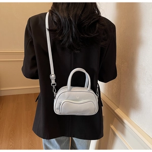 Détail du sac bandoulière bleu clair brillant avec ferrures argentées sur une veste