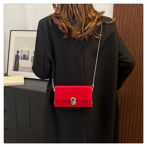 Close-up of vibrant red crossbody box bag featuring a silver twist lock and metal chain