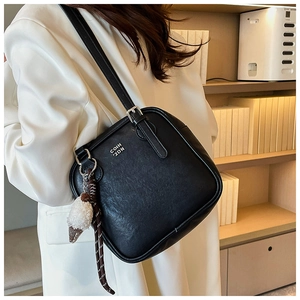 Close-up of black square shoulder bag with silver buckle and plush ice cream charm