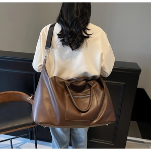 Détail du sac de voyage en cuir PU marron foncé avec bandoulière et ferrures argentées