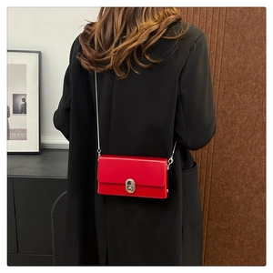Detail of red leather crossbody box bag with silver metal chain on black suit
