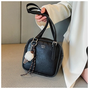 Detail of black faux leather bag with COIN '2DN text and plush ice cream charm
