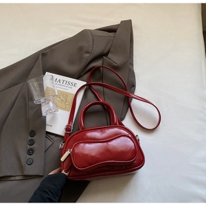 Détail d'un sac Boston rouge foncé brillant avec boucle métallique argentée élégante