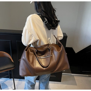 Grand sac de voyage marron foncé avec bandoulière réglable porté de vue arrière