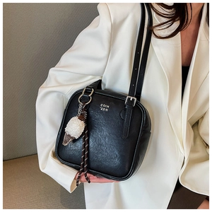 Detail of black leather underarm bag with plush ice cream charm and white logo