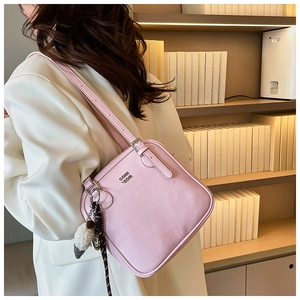 Detail view of pink leather underarm square bag with silver logo and plush charm