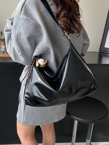 Large black patent leather Hobo tote bag with a baseball charm on a shoulder model