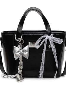 Chic black glossy bucket bag with silver heart charm and lace bow on white background