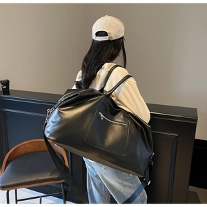 Vue détaillée du grand sac de voyage noir avec texture en simili cuir brillant et sangle