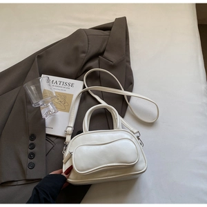 Vue détaillée du sac boston blanc en similicuir posé sur un blazer marron et un livre