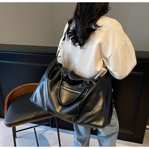 Détail d'un grand sac de voyage noir multifonctionnel porté par un mannequin