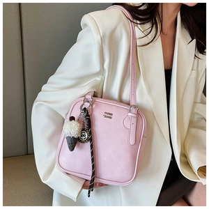 Detail of pink leather square handbag with metal logo and decorative charms
