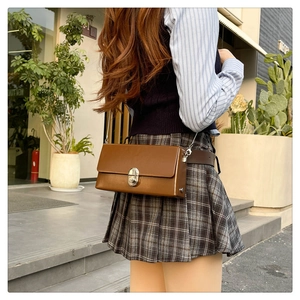 Close-up of a brown rectangular chain bag with silver twist lock on a casual street outfit