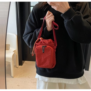 Detailliertes Spiegel-Selfie einer kompakten roten Umhängetasche aus Nylon mit Kordelzug