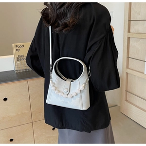 Close-up of white bucket bag featuring elegant pink beads and Youth & Elegant embossing