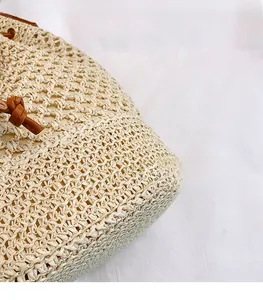 Detailed close-up of handmade straw bucket bag featuring hollow crochet weave and leather cord