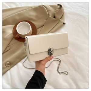 Detail of elegant cream faux leather crossbody bag with silver oval metal swivel lock