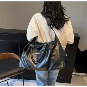 Modèle portant un grand sac de voyage noir avec fermetures éclair et bandoulière