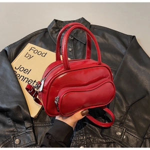Détail du mini sac Boston en cuir verni rouge avec accents argentés sur veste en cuir