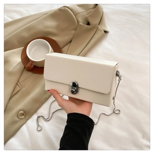 Detailed shot of cream white crossbody box bag with silver metal chain and twist lock