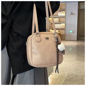 Detail of beige square shoulder bag with plush ice cream charm and silver logo