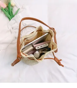 Top view of spacious interior of woven straw bucket bag with tablet and cosmetics