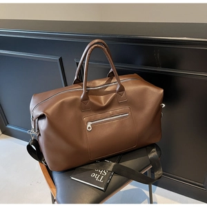 Détail du sac de voyage en cuir marron avec poignées robustes et fermetures éclair