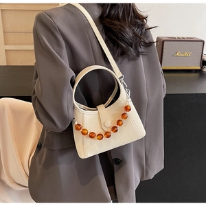 Detail of cream beaded handbag with amber beads and circular handle worn on shoulder