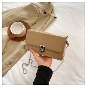 Close-up of khaki crossbody box bag with silver metal twist lock and chain strap