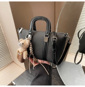 Detail of black woven textured bucket bag with cute bear charm and silver matte hardware