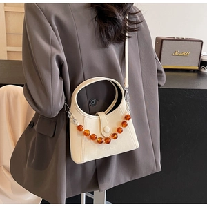 Detail of cream PU leather bucket bag with amber beaded chain and crossbody strap