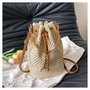 Close-up of woven straw bucket bag featuring brown leather drawstring and strap