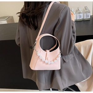 Detail of pink beaded handbag with pearl chain and leather texture on a grey blazer