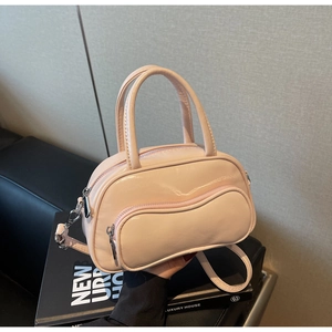 Détail du sac Boston en cuir verni rose brillant avec poche zippée ondulée et bandoulière
