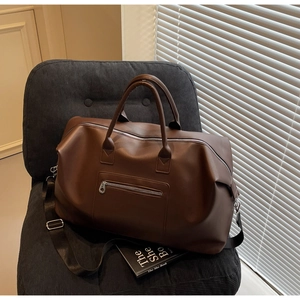 Détail du sac de voyage en similicuir marron avec des fermetures éclair métalliques