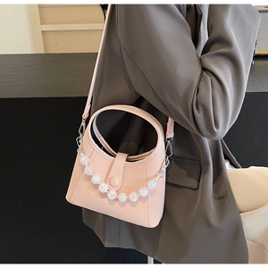 Detail of light pink PU leather bucket bag with elegant white pearl decorative chain
