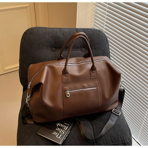Détail d'un grand sac de voyage marron, texture cuir avec bandoulière réglable