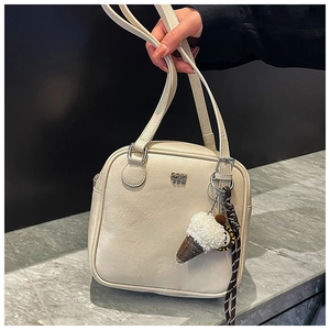 Detail of cream crossbody bag with leather texture, metal logo and ice cream charm