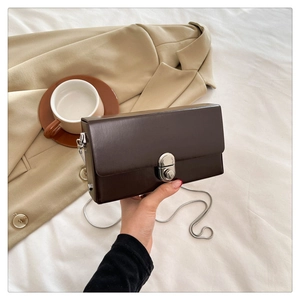Detailed view of dark brown box bag with silver rotary metal lock and fine chain strap