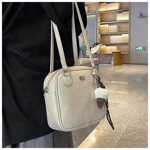 Detail of cream square shoulder bag with silver zipper and ice cream charm accessory