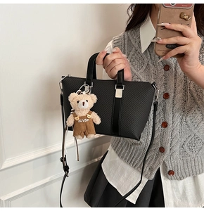 Detail of black woven texture handbag featuring a cute teddy bear charm with SUVSP logo