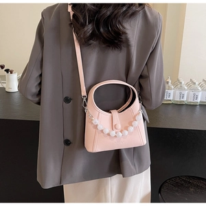 Detailed back view of a light pink beaded bucket bag with elegant pearl chain and round handle