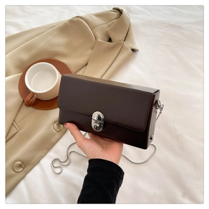 Detail of coffee brown chain crossbody box bag with silver buckle and sleek faux leather finish