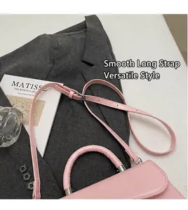 Dettaglio di una borsa in pelle opaca rosa con tracolla regolabile su una giacca grigia