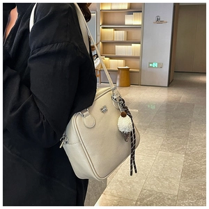 Close-up of cream square shoulder bag with metal logo and plush ice cream charm detail