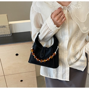 Detail of matte black leather bucket bag featuring unique amber bead handle decoration