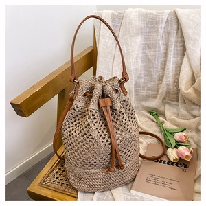 Top view of hand-woven straw bucket bag with leather drawstring on a wooden rattan chair